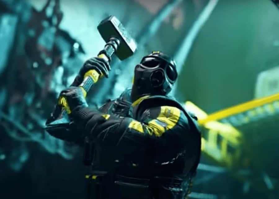 Rainbow Six Siege Sledge 桌布 壁紙 — 一個戴面具的人物身穿黑色和黃色裝備，在昏暗的工業環境中舉起沉重的錘子。