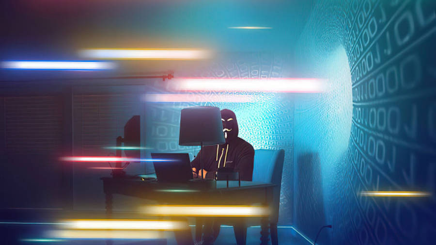 hacker 3d 桌布 壁紙 — 一個戴面具的黑客坐在一張發光的桌子前，被數位代碼和霓虹燈光條包圍，身處賽博龐克環境中。