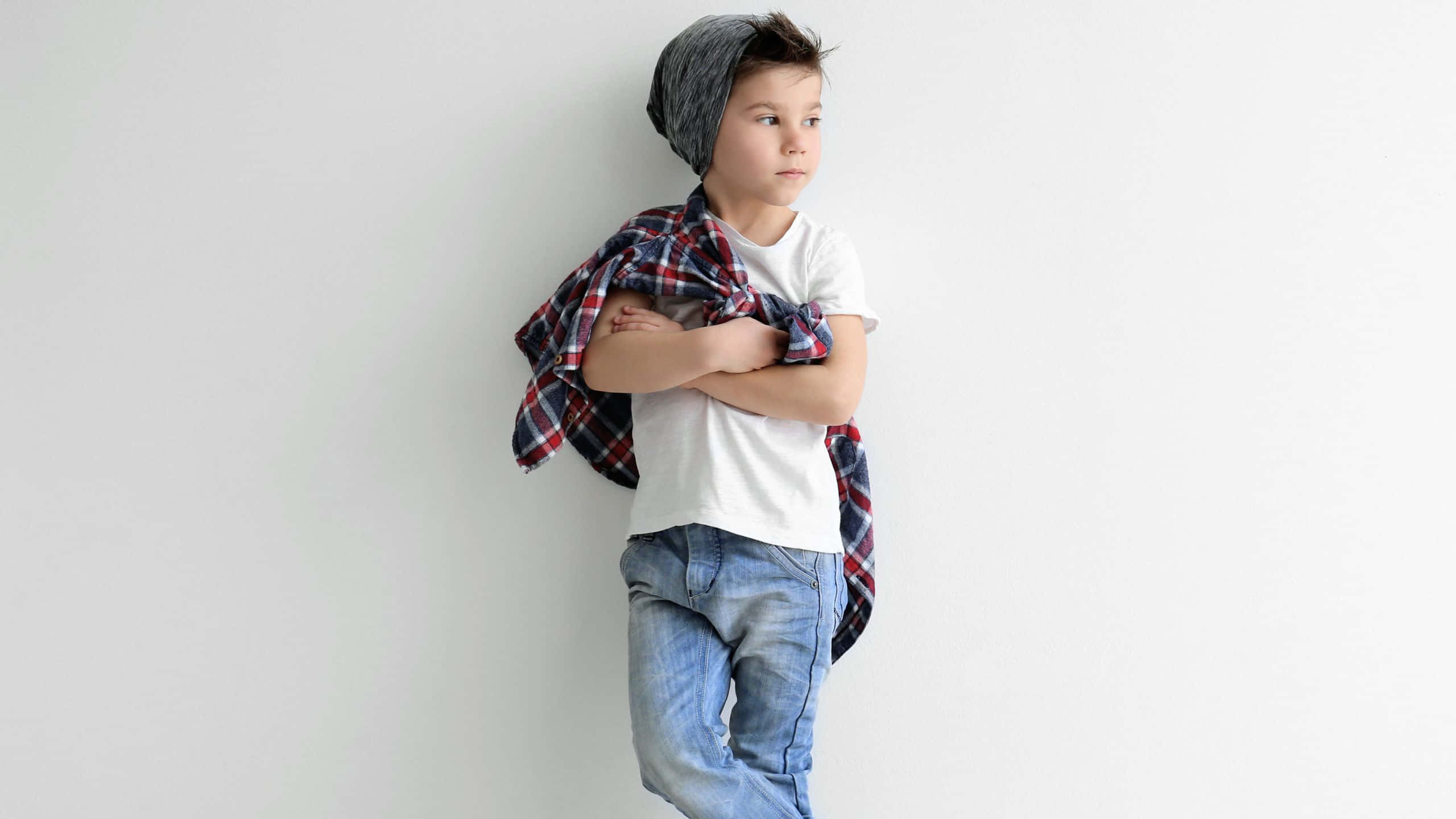 Cute Boy 桌布 壁紙 — 一個戴頭巾和穿格紋襯衫的年輕男孩交叉雙臂靠在一面純白牆上。