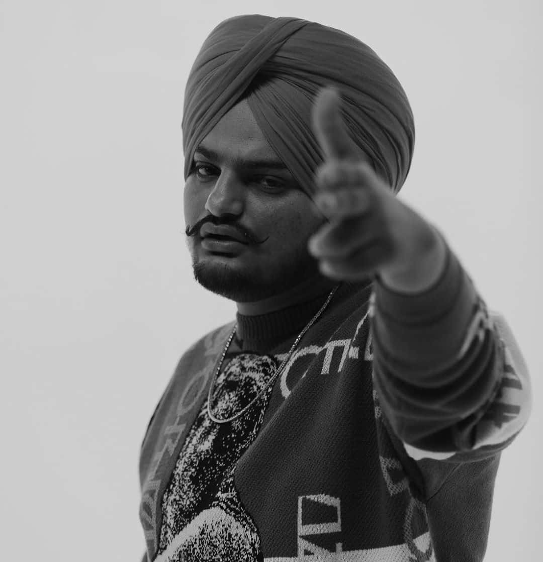 戴頭巾的男人在黑白工作室肖像中指向觀眾 — Sidhu Moose Wala 壁紙