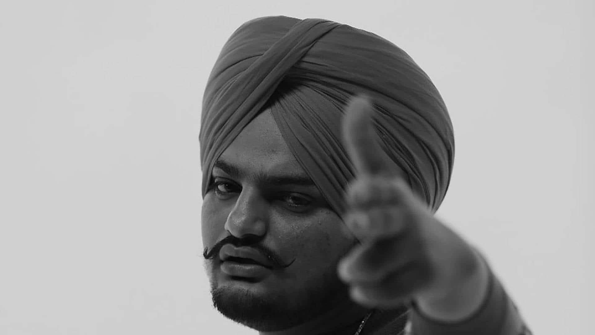 一個戴頭巾的男人表情嚴肅地直接指向相機。 — Sidhu Moose Wala 壁紙