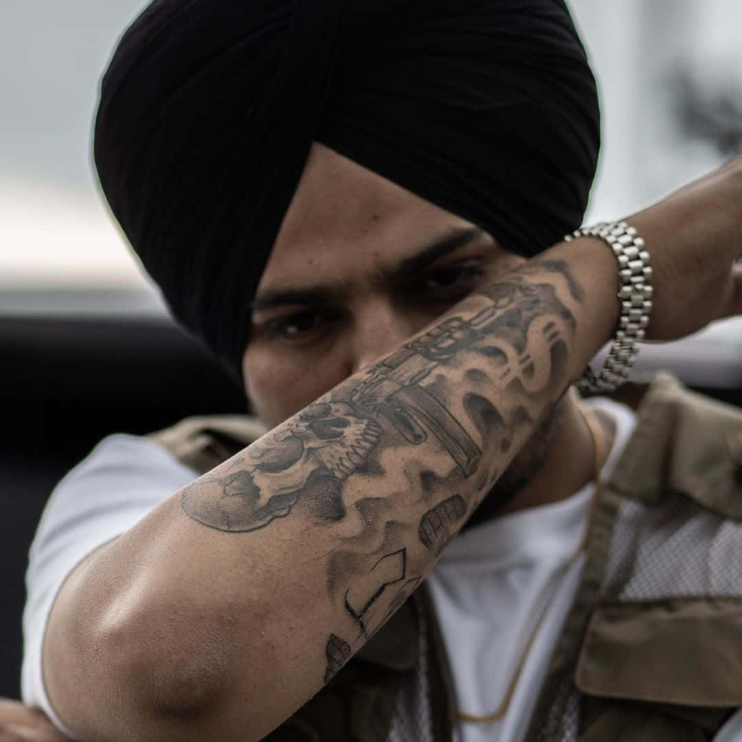 戴黑色頭巾的男人，紋身手臂遮住臉 — Sidhu Moose Wala 壁紙