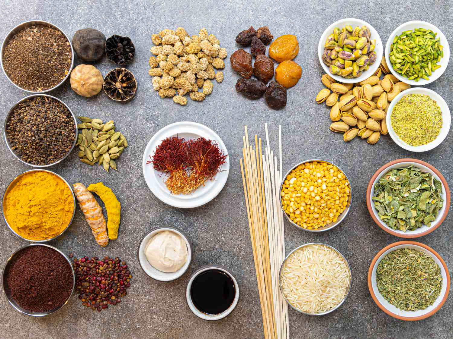 烹飪 桌布 壁紙 — 一個扁平佈局，將充滿活力的香料、香草和食材（如藏紅花、薑黃、開心果和扁豆）整齊地排列在灰色表面上。