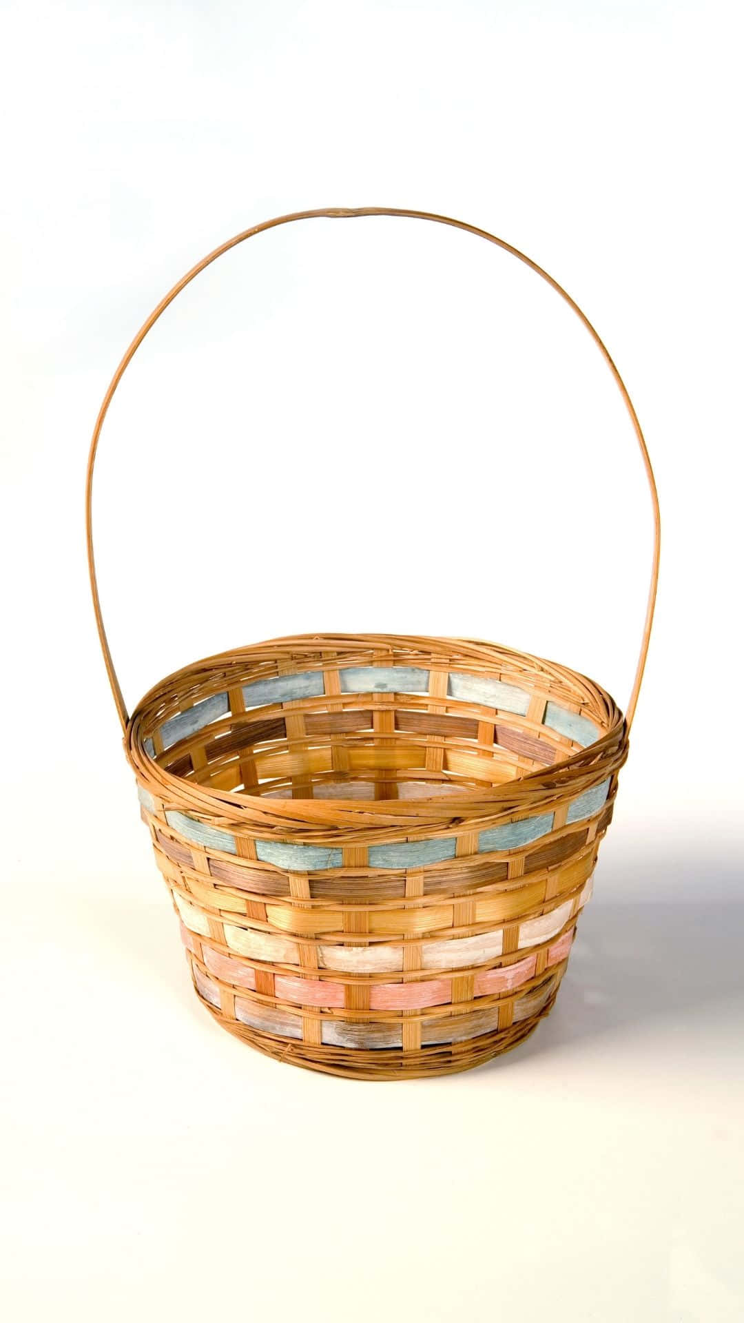 Easter Basket 桌布 壁紙 — 一個手工編織的籃子，帶有彎曲的木手柄和粉彩繪畫的條帶，位於明亮的白色背景中央。