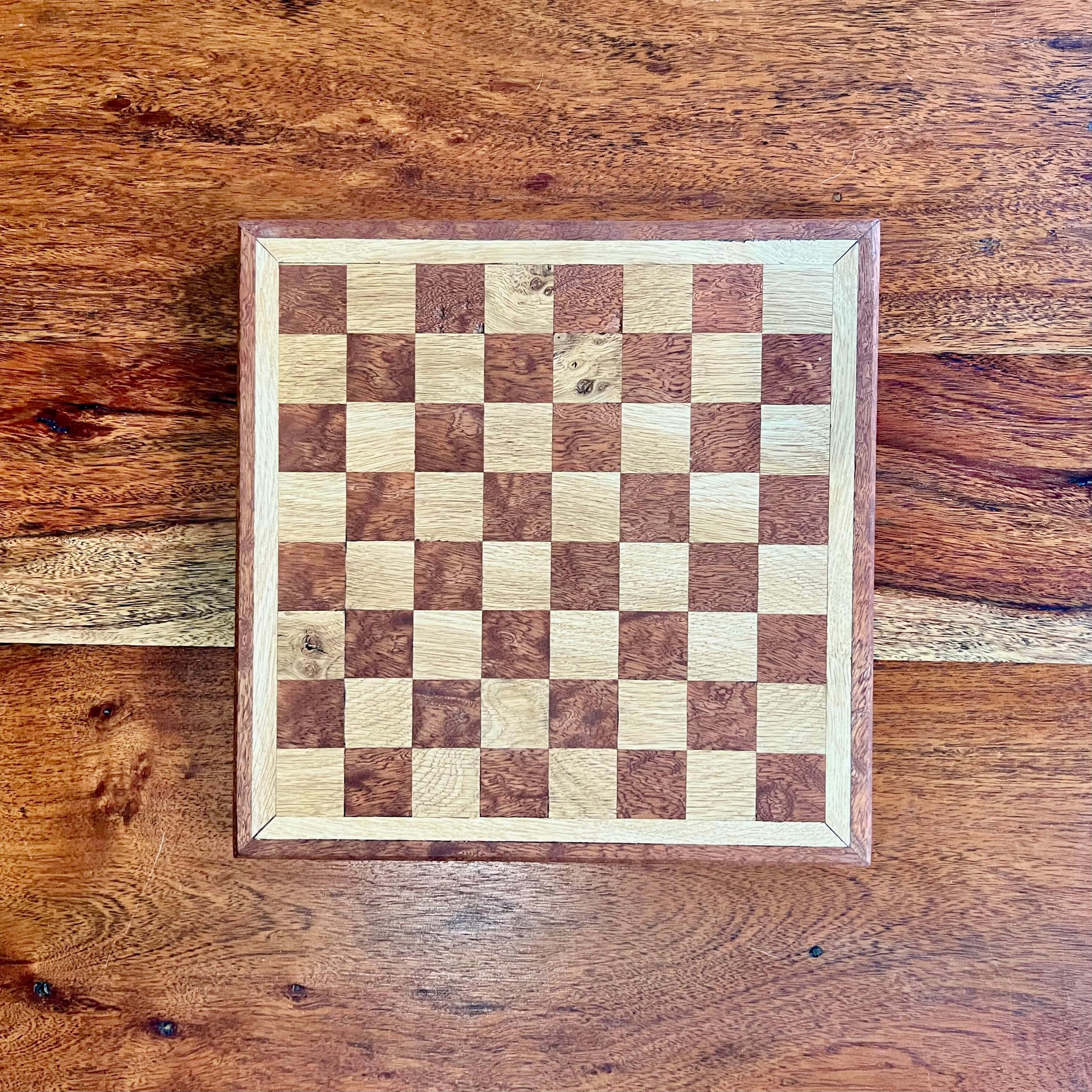 Chessboard 桌布 壁紙 — 一個手工製作的木製棋盤，帶有豐富的木紋圖案，放置在質樸的木桌中央。