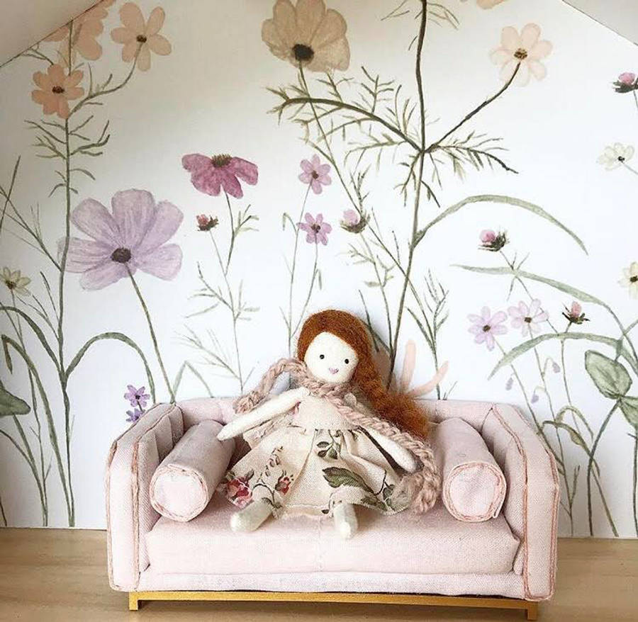 Dollhouse 桌布 壁紙 — 一個手工製作的洋娃娃，有棕色毛線頭髮，坐在迷你粉紅色沙發上，背景是花卉壁紙。