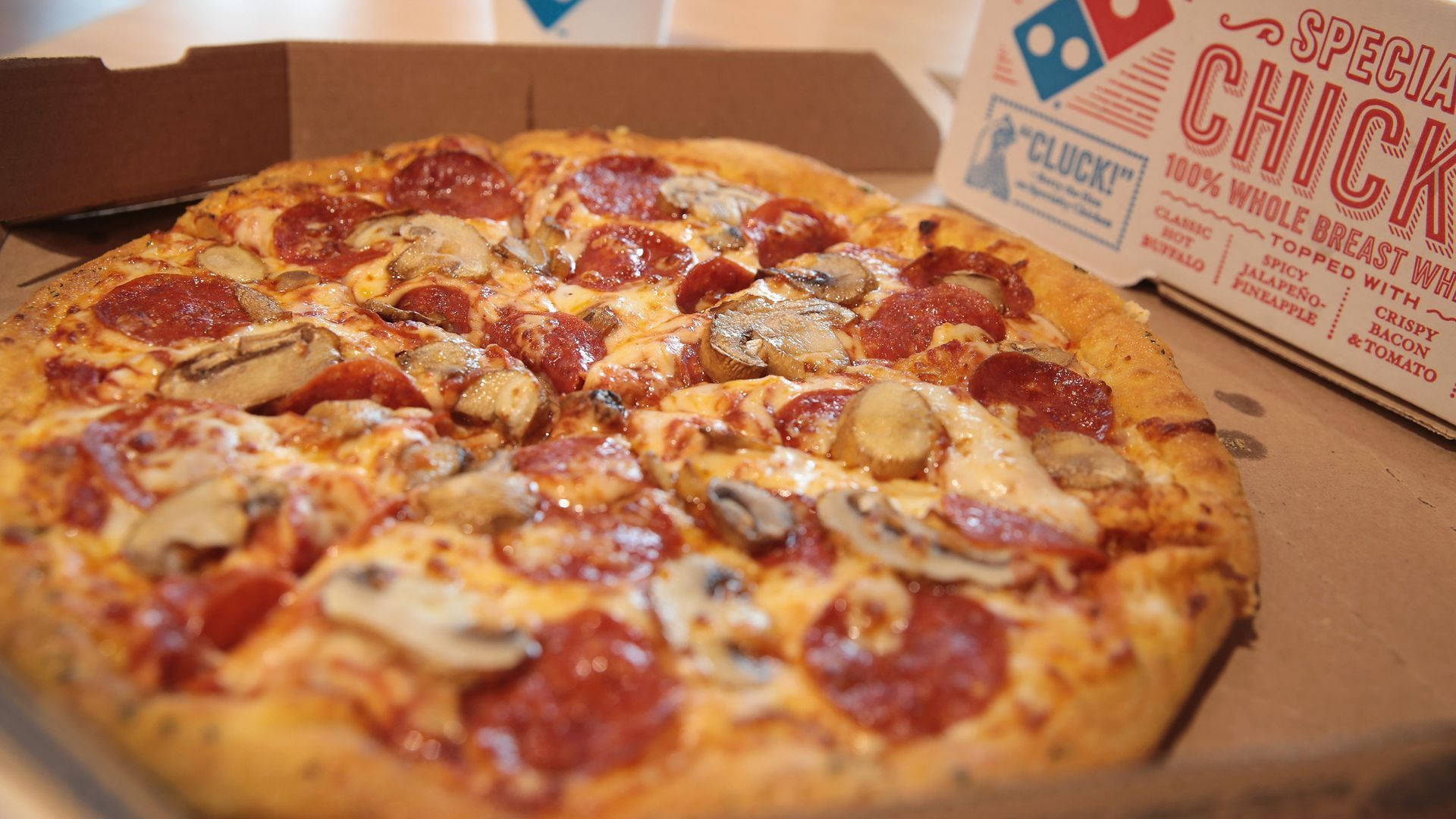 Dominos Pizza 桌布 壁紙 — 一個打開的Domino's盒子裡，有義大利辣香腸和蘑菇披薩的特寫，帶有融化的起司和金黃色的外皮。