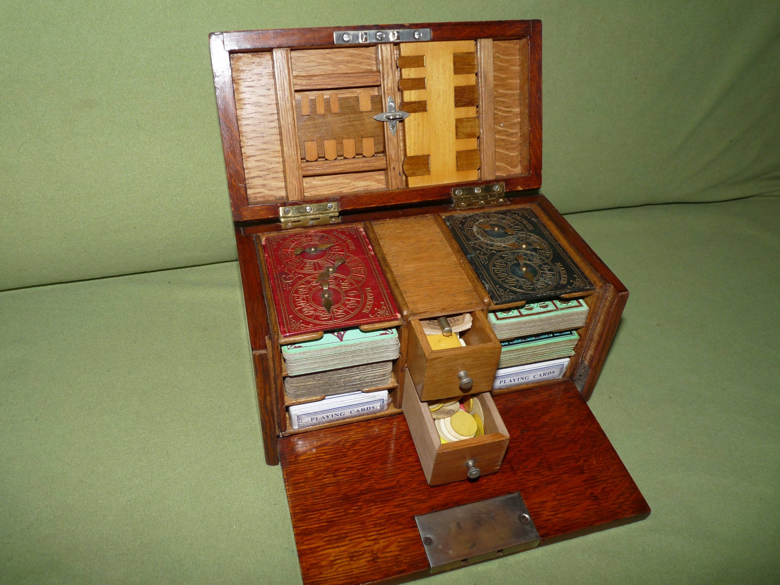 Box 桌布 壁紙 — 一個打開的復古木製遊戲盒，露出帶有撲克牌、骰子和精緻鑲嵌木工的隔層，背景為綠色布料。