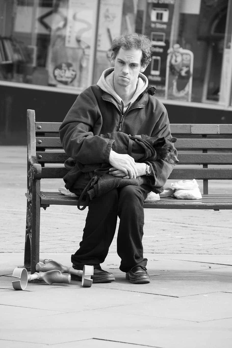 Sad Face 桌布 壁紙 — 一個拄著拐杖的男人癱坐在城市廣場的長椅上，黑白畫面中顯得疲憊而沉思。