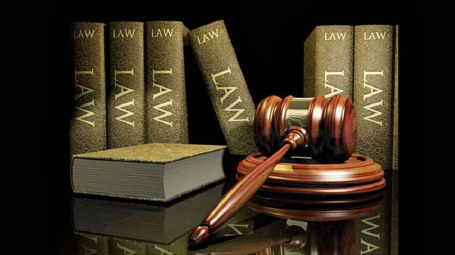 Advocate 桌布 壁紙 — 一個拋光木槌放在其支架上，旁邊是帶有金色字體的法律書籍，置於反光的黑色表面上。