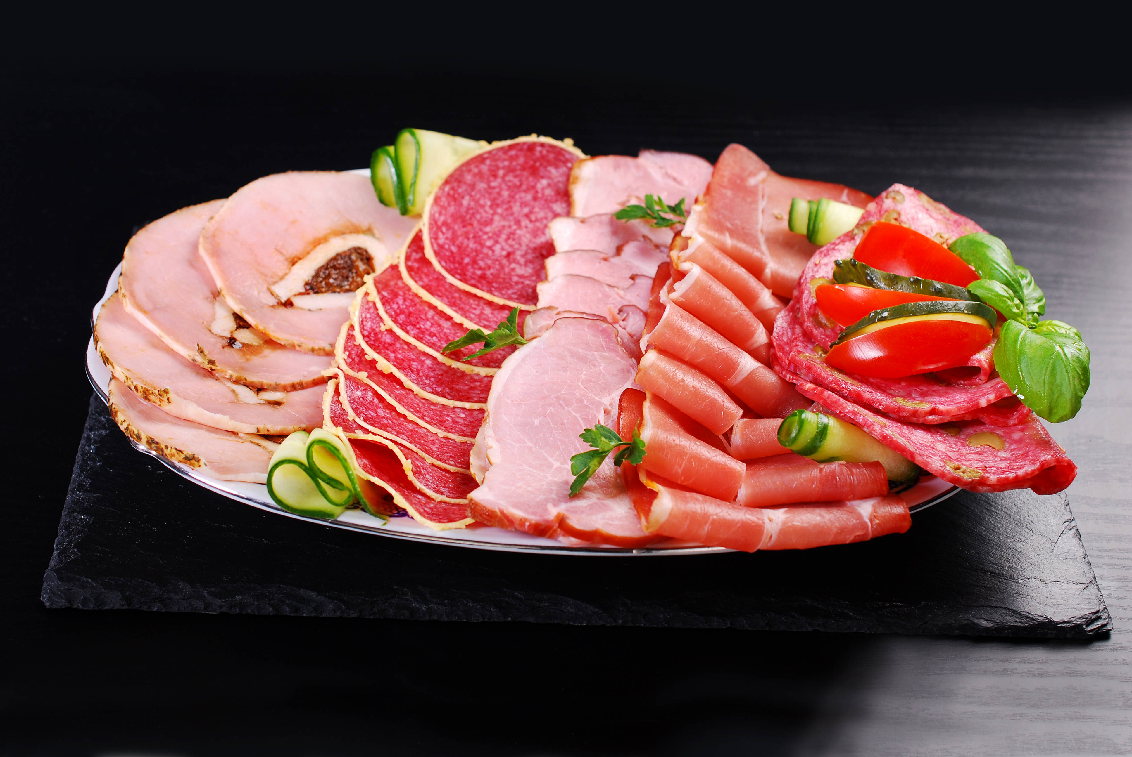 meat 桌布 壁紙 — 一個拼盤，上面有各種醃製肉類和新鮮蔬菜，藝術地擺放在深色石板板上。