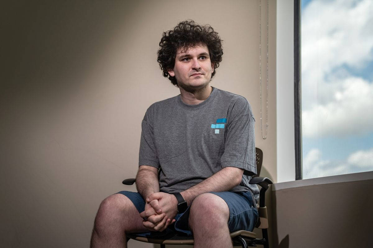 桌布 壁紙 — 一個捲髮年輕男子安靜地坐在室內的椅子上，若有所思地望向窗外明亮的陰天。