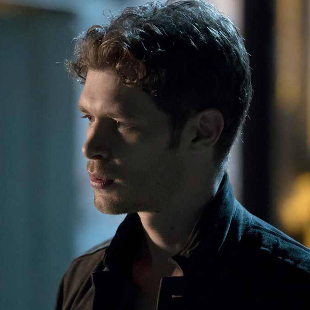 Vampire Diaries 桌布 壁紙 — 一個捲髮男人在昏暗燈光下若有所思地凝視，柔和陰影凸顯他的側面輪廓。