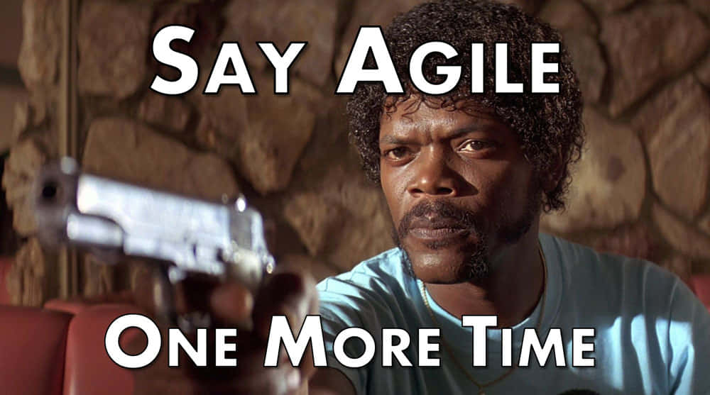 Time Management Memes 桌布 壁紙 — 一個捲髮男人手持槍枝向前指，表情強烈，背景是石牆。