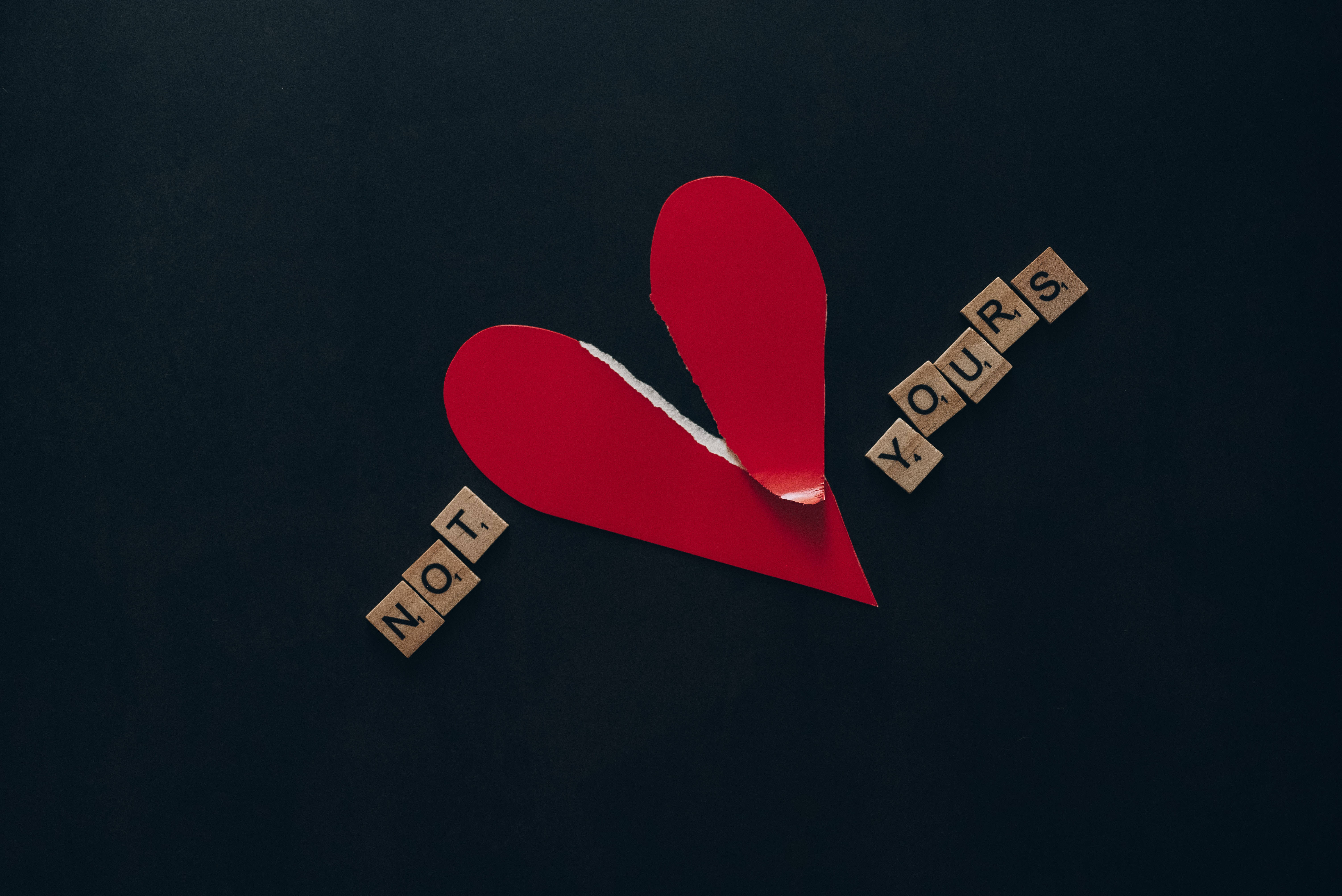 心碎 桌布 壁紙 — 一個撕裂的紅色紙愛心分裂開，帶有拼出「NOT YOURS」的木塊，在深色紋理背景上。
