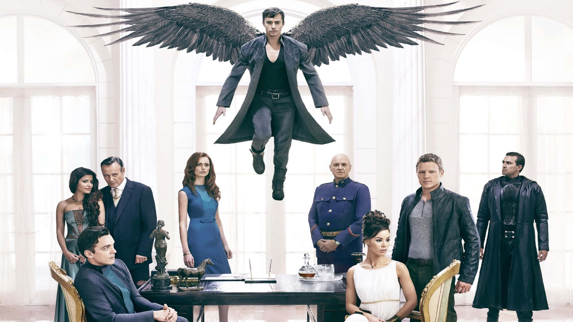 Tv Series 桌布 壁紙 — 一個擁有巨大黑色翅膀的男人在一個有拱形窗戶的明亮白色房間裡盤旋在八個人之上。