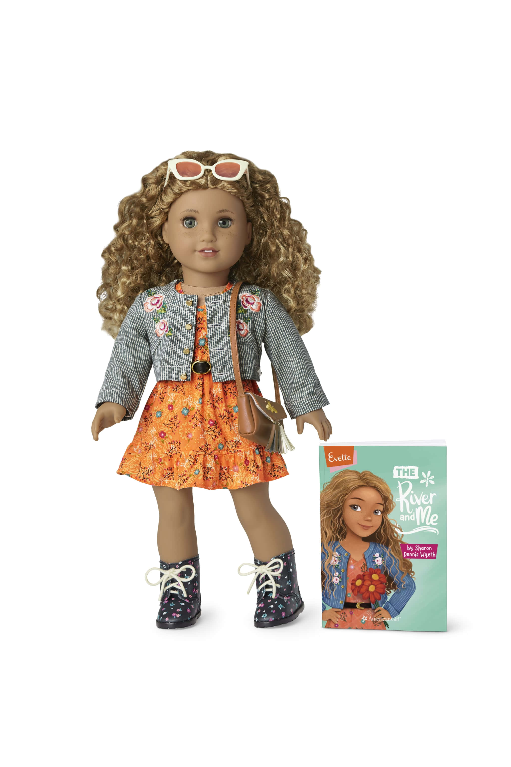 american girl 桌布 壁紙 — 一個擁有捲髮和太陽眼鏡的洋娃娃，穿著花卉圖案的連衣裙和外套，旁邊放著與之相配的書。