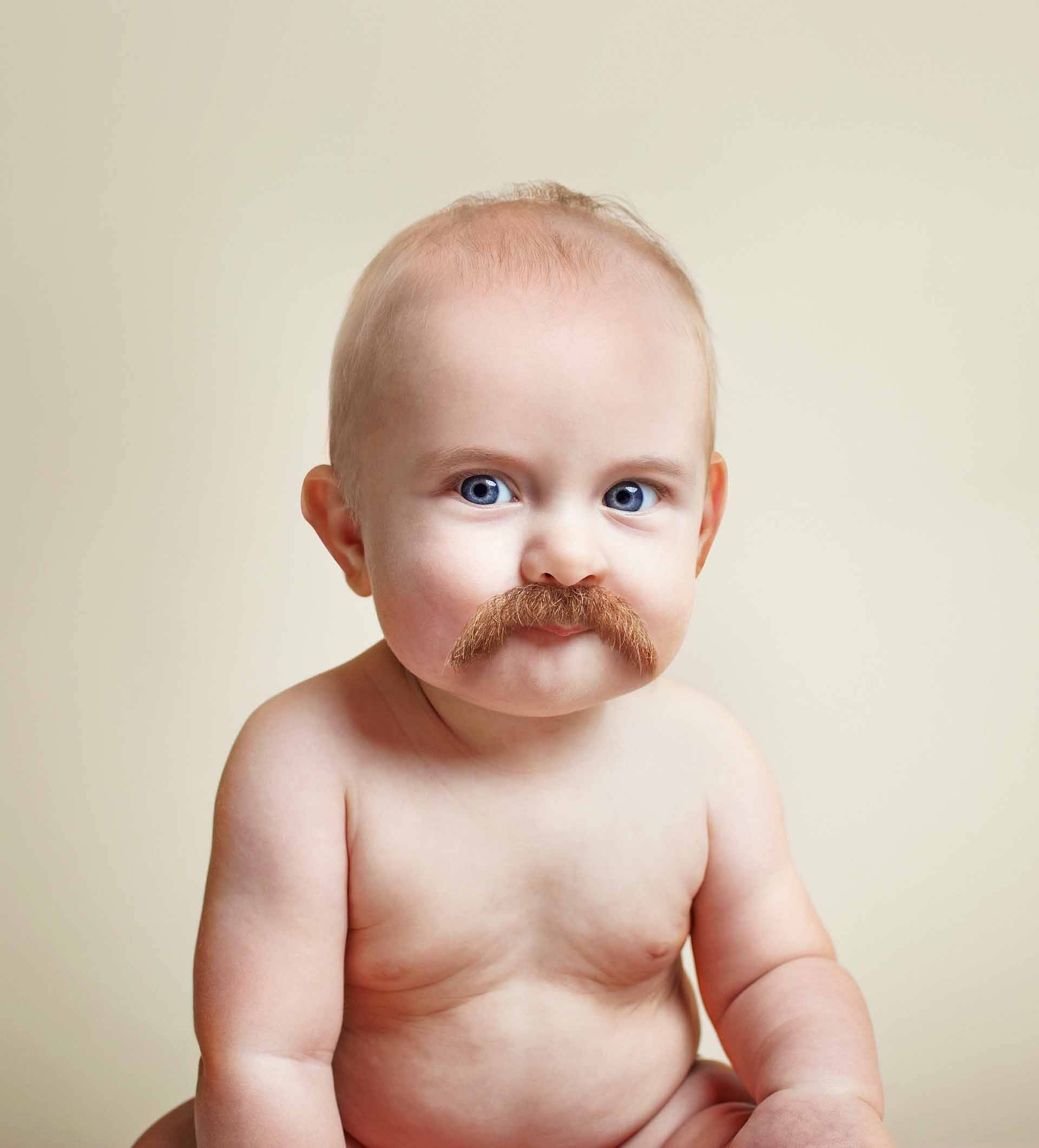 Funny Baby 桌布 壁紙 — 一個擁有明亮藍眼睛和棕色鬍子的嬰兒坐在純米色背景前。