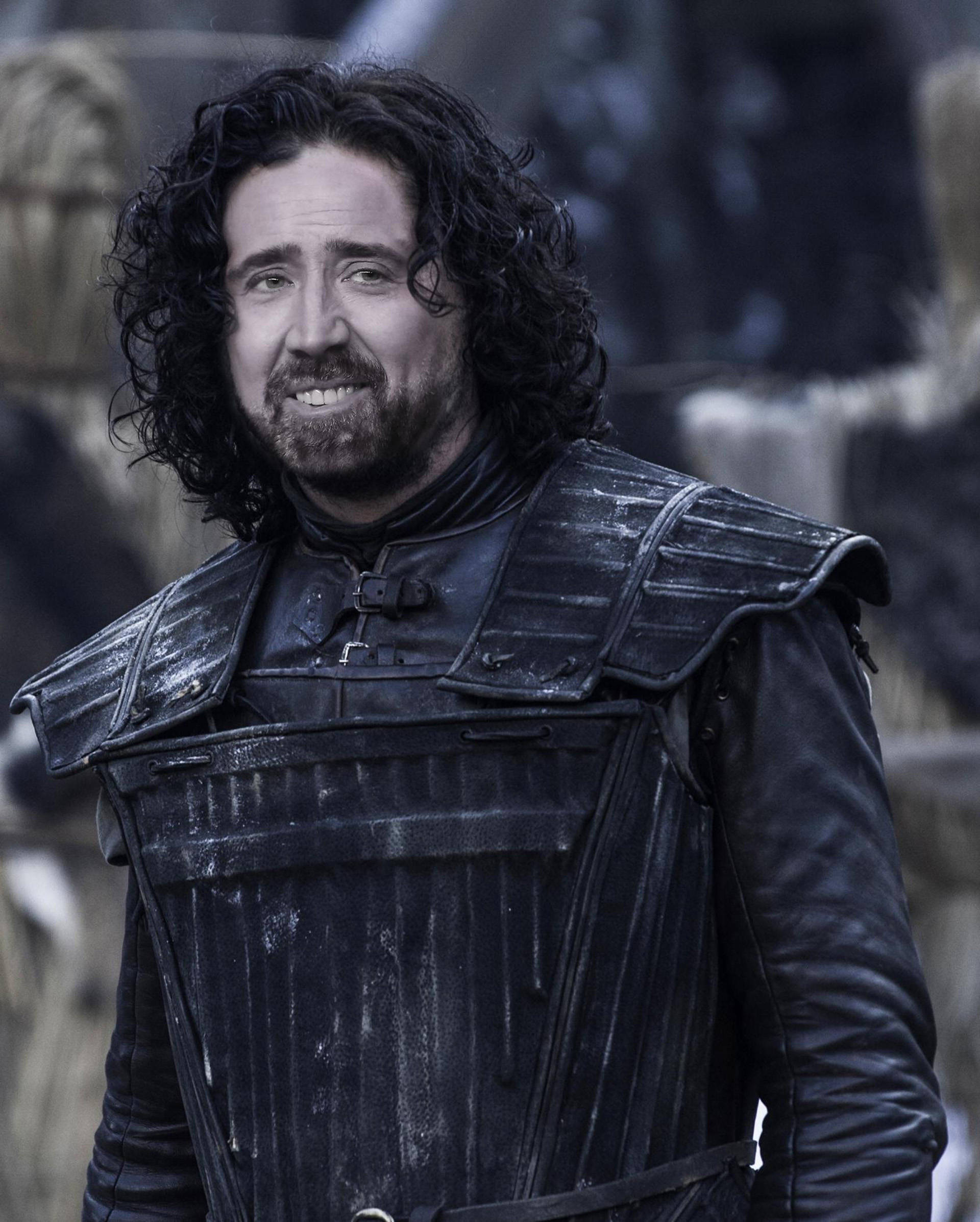 nicolas cage meme 桌布 壁紙 — 一個擁有深色長捲髮和鬍鬚的男人，穿著風化的黑色盔甲，露出自信的微笑。