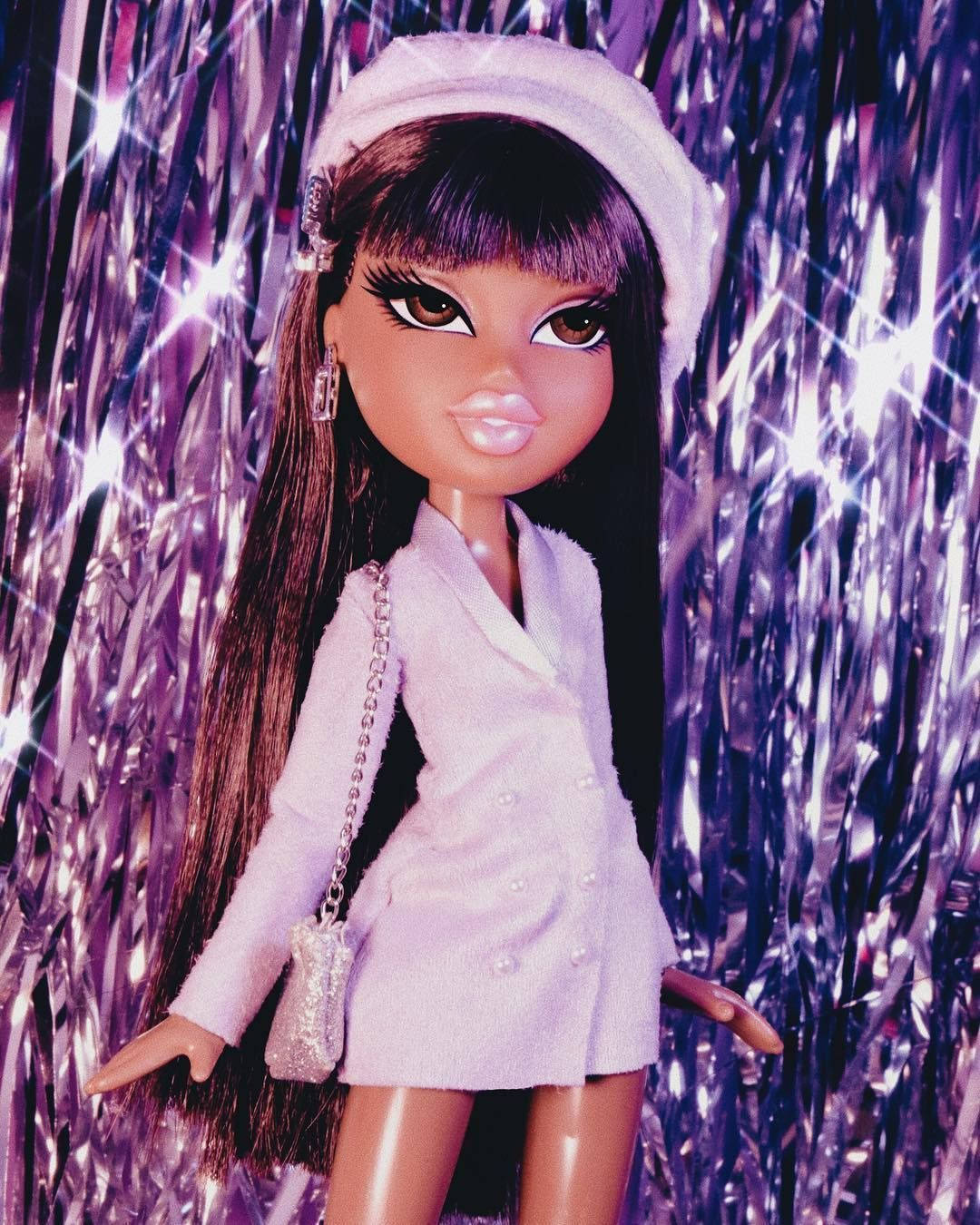 Bratz 桌布 壁紙 — 一個擁有深色長髮和白色貝雷帽的洋娃娃，自信地站在閃閃發光的紫色金屬箔背景前。