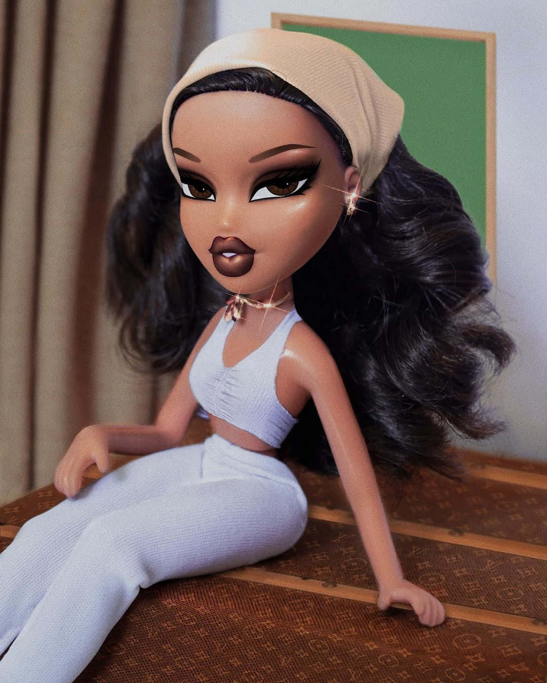 bratz 美學 桌布 壁紙 — 一個擁有深色長髮和米色頭帶的 Bratz 娃娃自信地坐在棕色圖案表面上，穿著白色家居服。