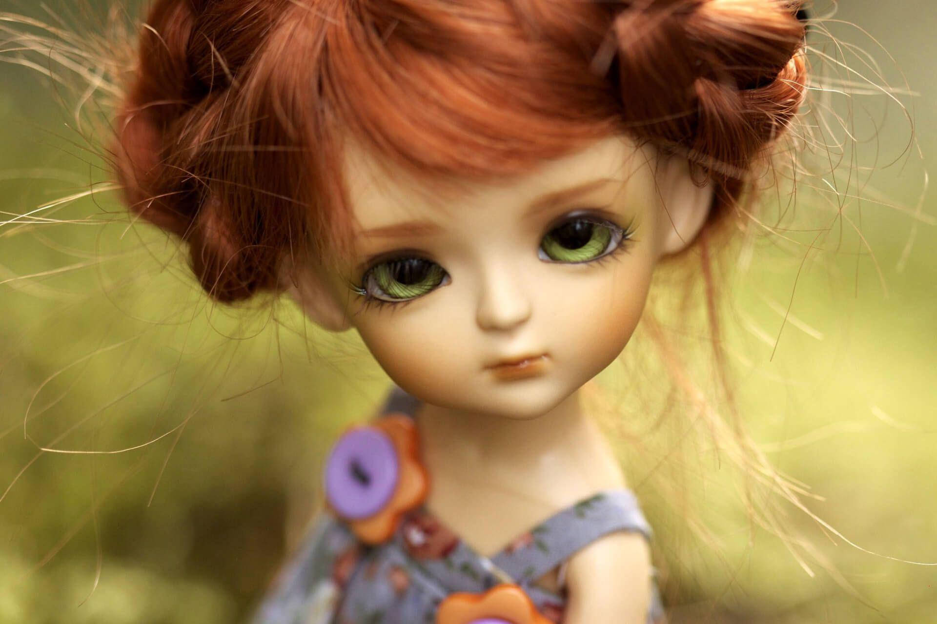 Doll 桌布 壁紙 — 一個擁有火紅頭髮和大綠眼睛的洋娃娃特寫，在模糊的綠色背景下溫柔地凝視。
