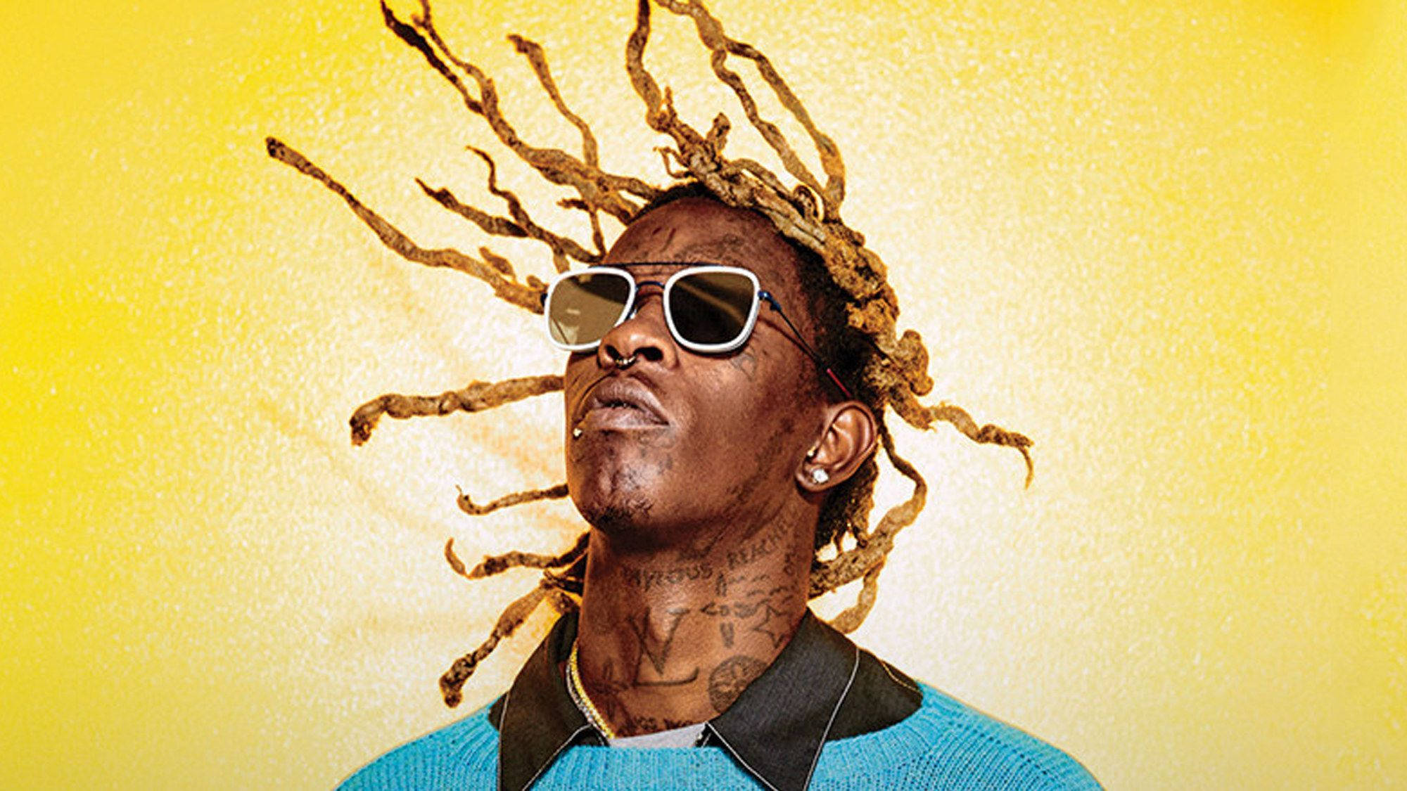 Thug 桌布 壁紙 — 一個擁有狂野辮子頭和太陽眼鏡的男人，在充滿活力的黃色紋理背景上向上凝視。