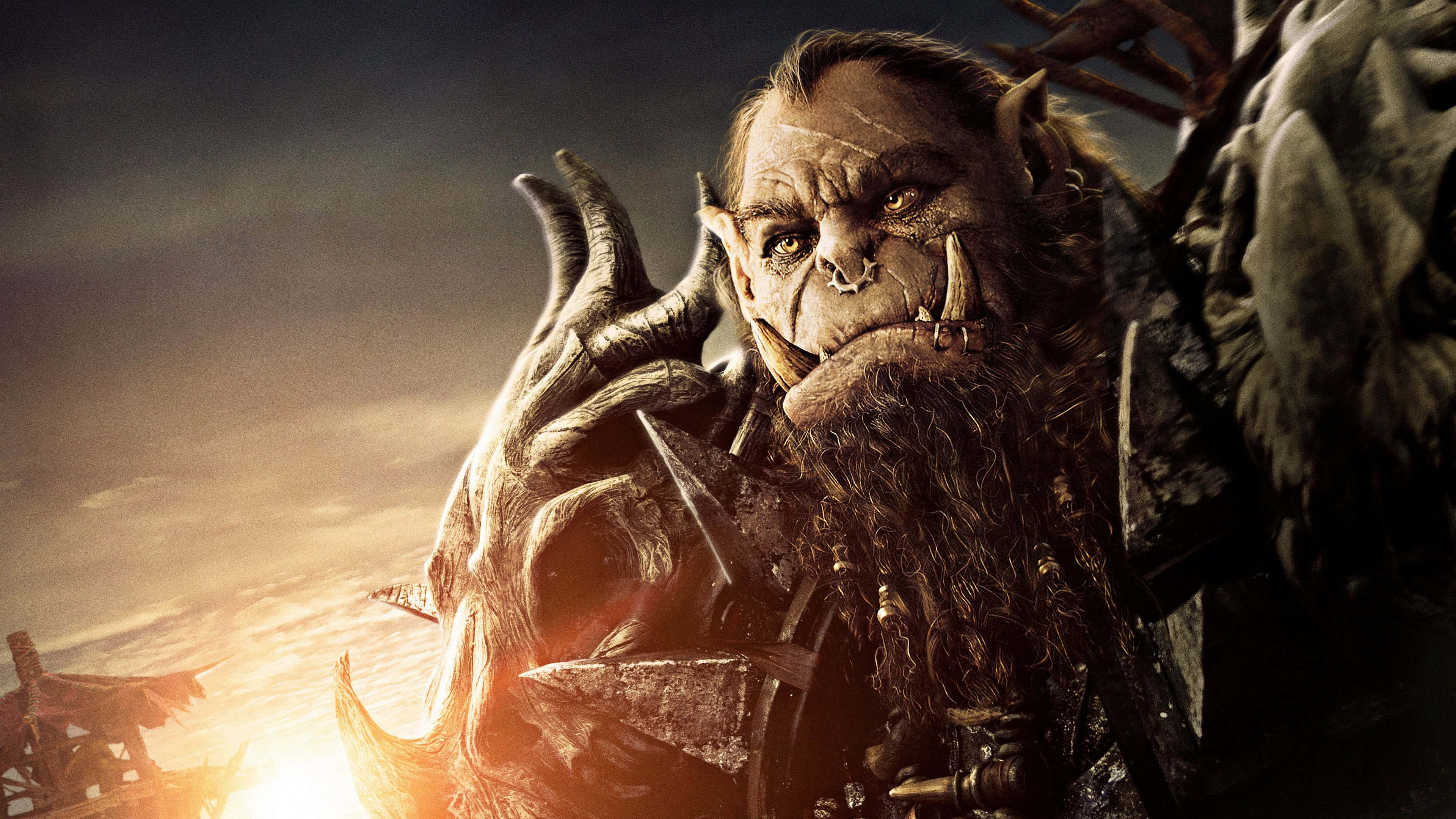 Warcraft 2 桌布 壁紙 — 一個擁有獠牙和角的兇猛獸人戰士，在熾熱的日落背景下強烈地凝視著。