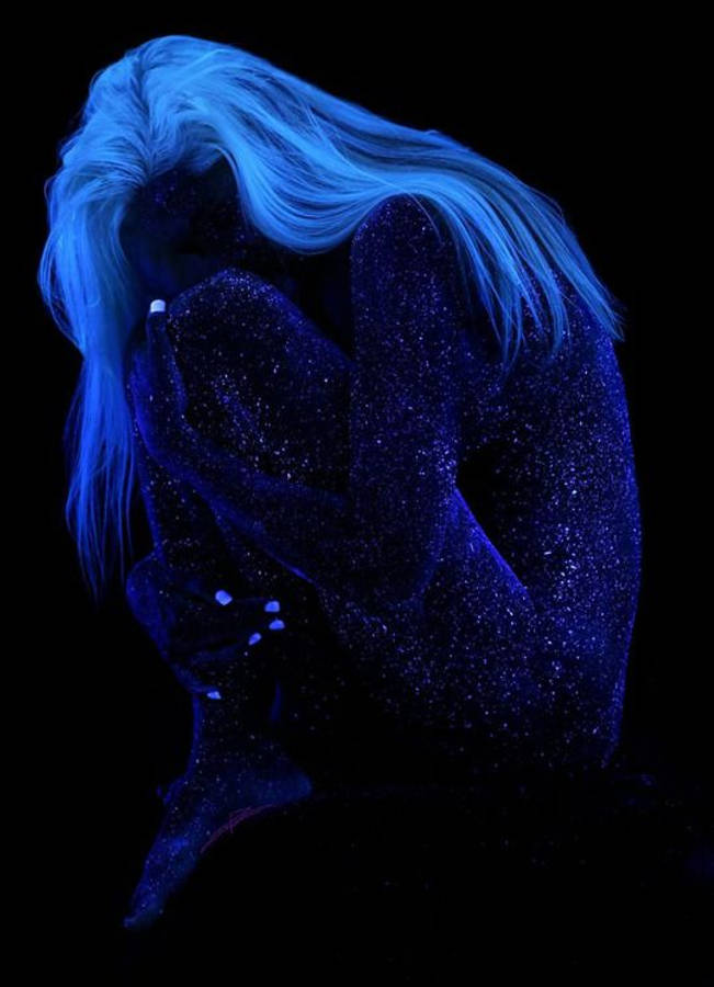 dark blue aesthetic tumblr 桌布 壁紙 — 一個擁有發光藍色頭髮和閃爍藍色皮膚的人蜷縮在黑暗中，雙手遮臉，形成發光的剪影。