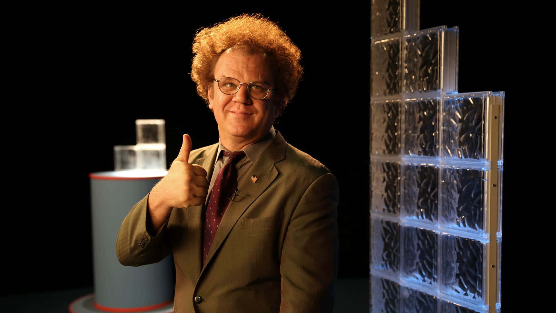 John C. Reilly 桌布 壁紙 — 一個擁有紅色捲髮和眼鏡的男人在一個帶有發光玻璃磚結構的工作室裡豎起大拇指。