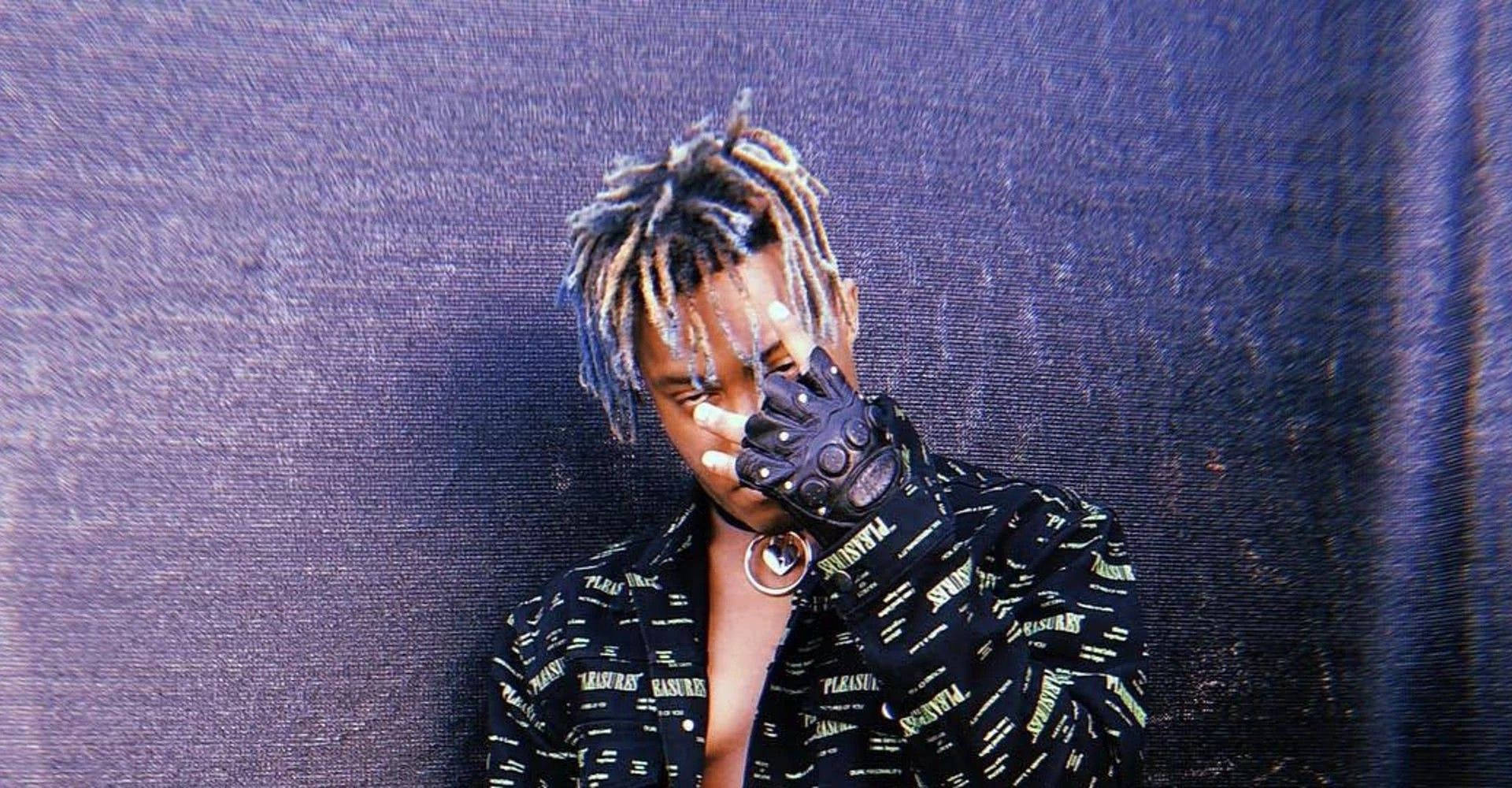 Juice Wrld Desktop 桌布 壁紙 — 一個擁有色彩繽紛辮子的人，戴著黑色手套遮住臉，背景是帶紋理的紫色。