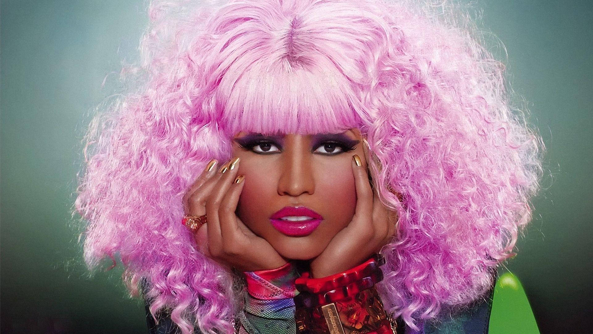 Nicki 桌布 壁紙 — 一個擁有豐盈粉紅捲髮和大膽妝容的人，在柔和的綠色背景前用手托著臉。