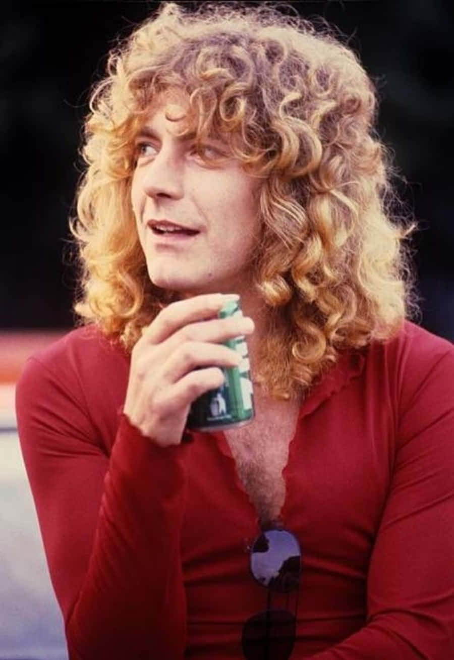 robert plant 桌布 壁紙 — 一個擁有豐盈金色捲髮的男人，穿著紅色襯衫，太陽眼鏡低掛，手持一個綠色罐子。