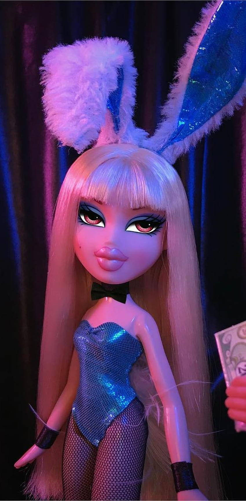 Bratz 桌布 壁紙 — 一個擁有金色長髮和閃亮藍色兔耳的公仔，在戲劇性的紫色燈光下穿著閃亮緊身衣擺姿勢。