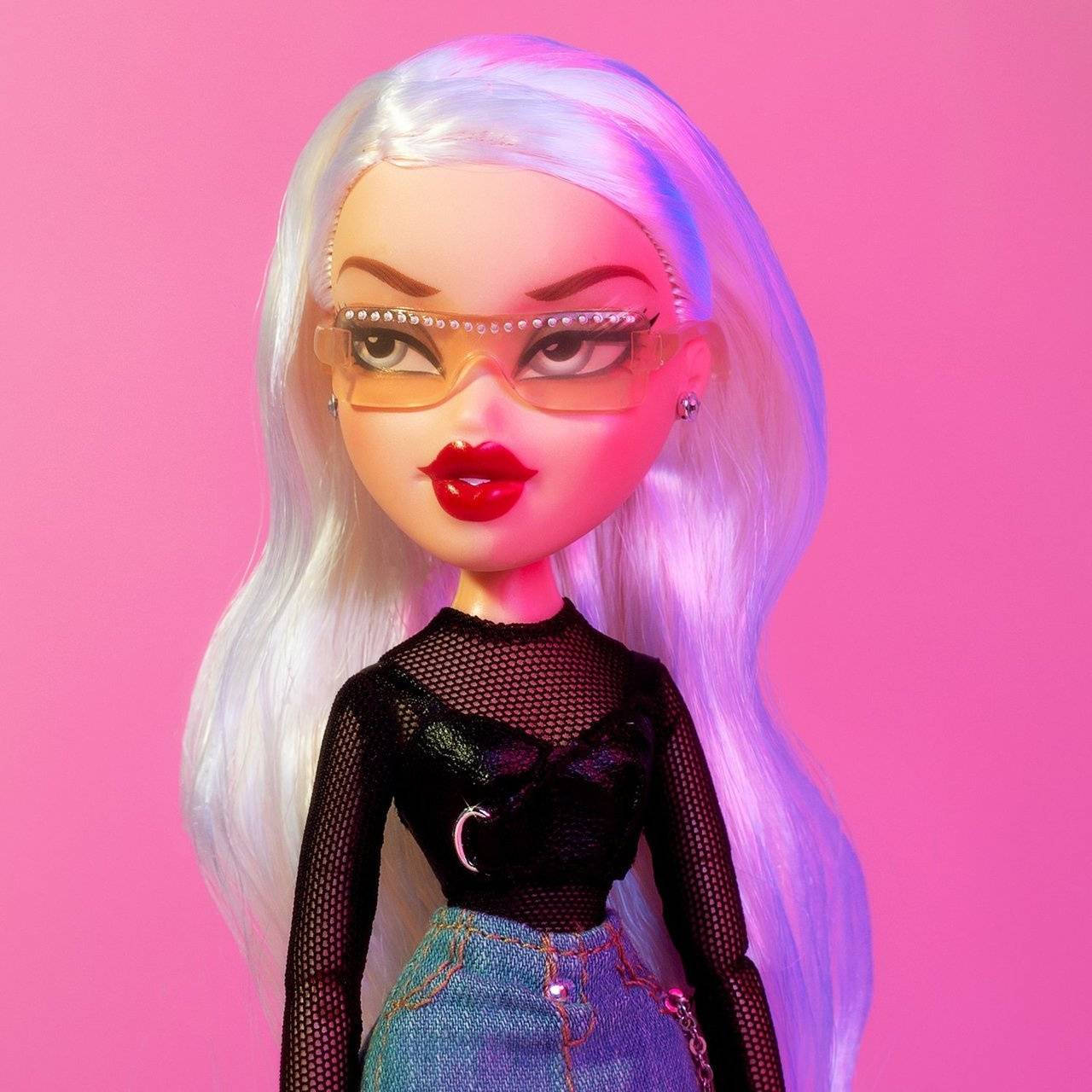 Bratz 桌布 壁紙 — 一個擁有鉑金色頭髮和大膽紅唇的玩偶，在充滿活力的粉紅色背景下戴著超大眼鏡。