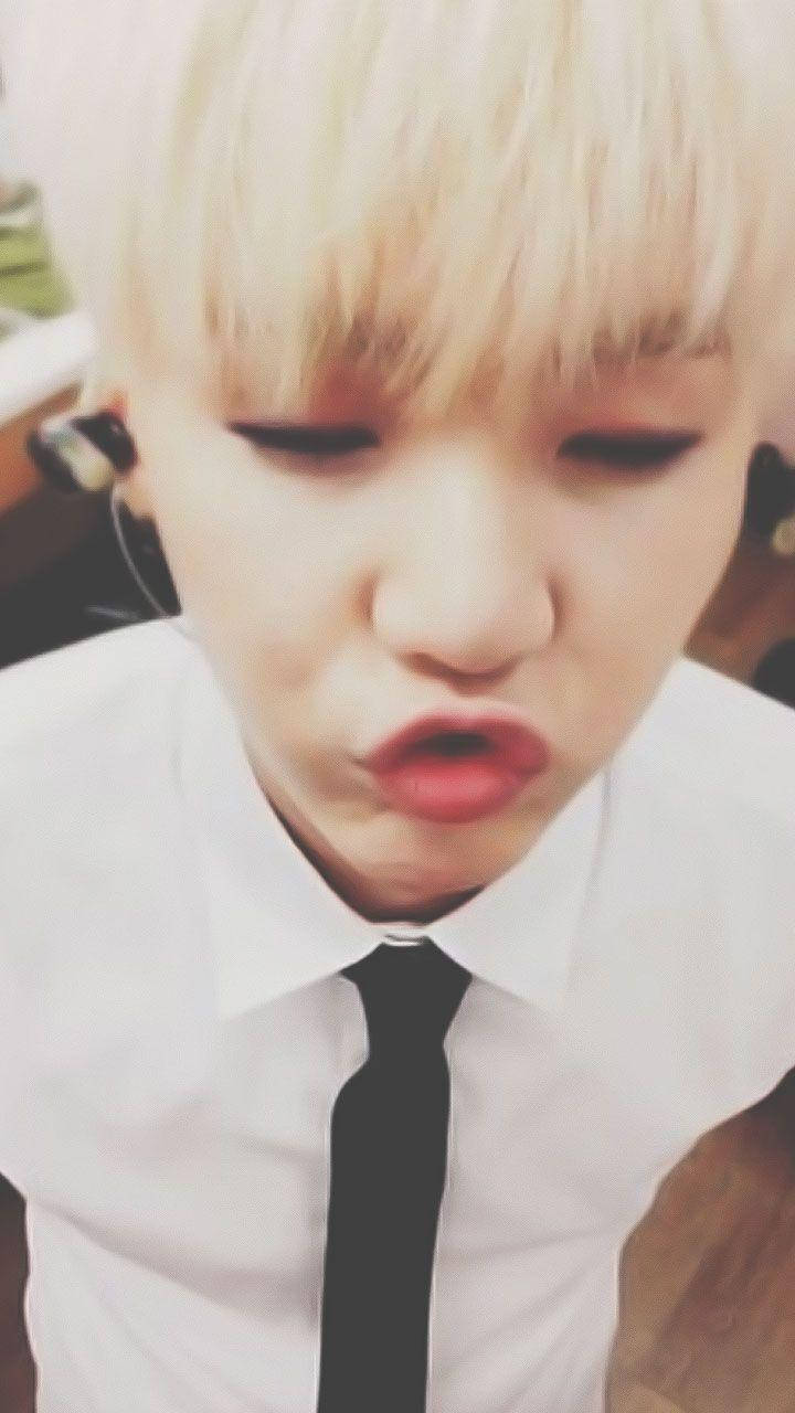 Suga Bts 桌布 壁紙 — 一個擁有鉑金色頭髮和紅唇的人，穿著白襯衫和黑色領帶，做出俏皮的嘟嘴表情的特寫。