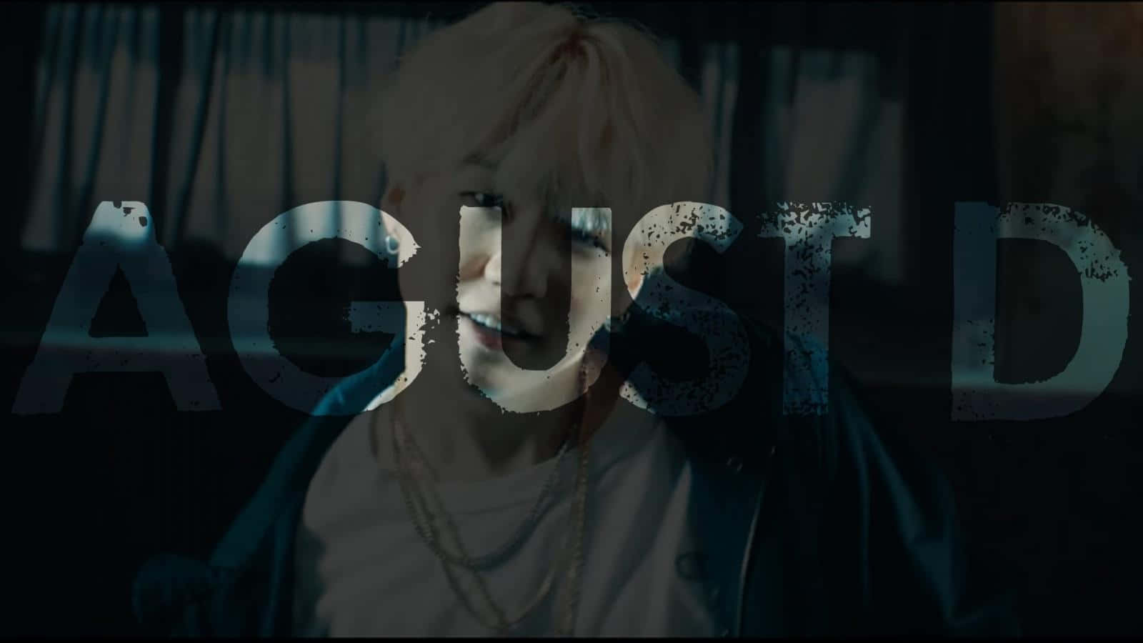 Agust D 桌布 壁紙 — 一個擁有鉑金色頭髮的人，在昏暗的房間裡透過破舊的文字疊加層凝視著。