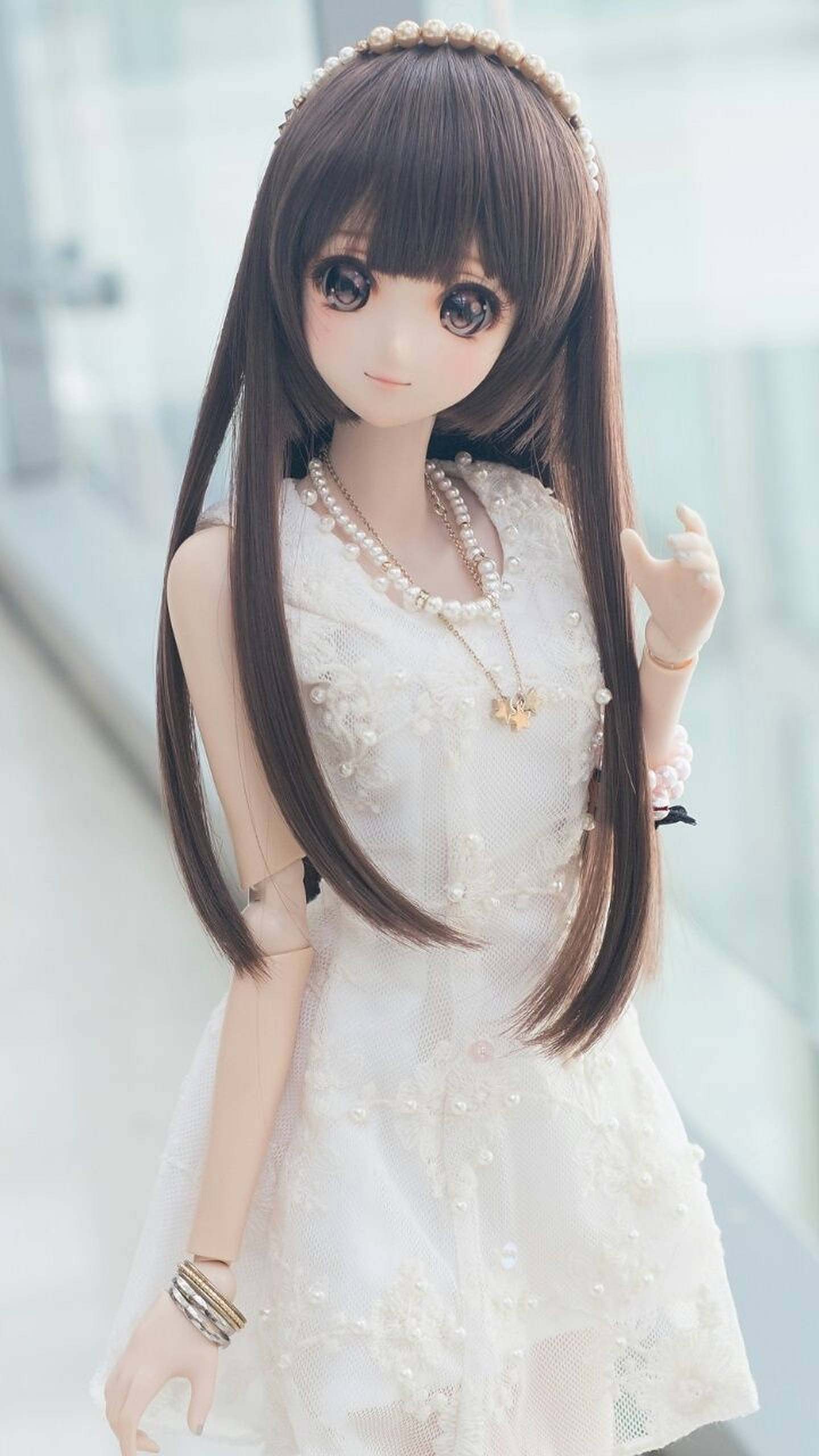 Doll 桌布 壁紙 — 一個擁有長長棕色頭髮和珍珠配飾的洋娃娃，穿著精緻的白色蕾絲連衣裙，背景明亮模糊。