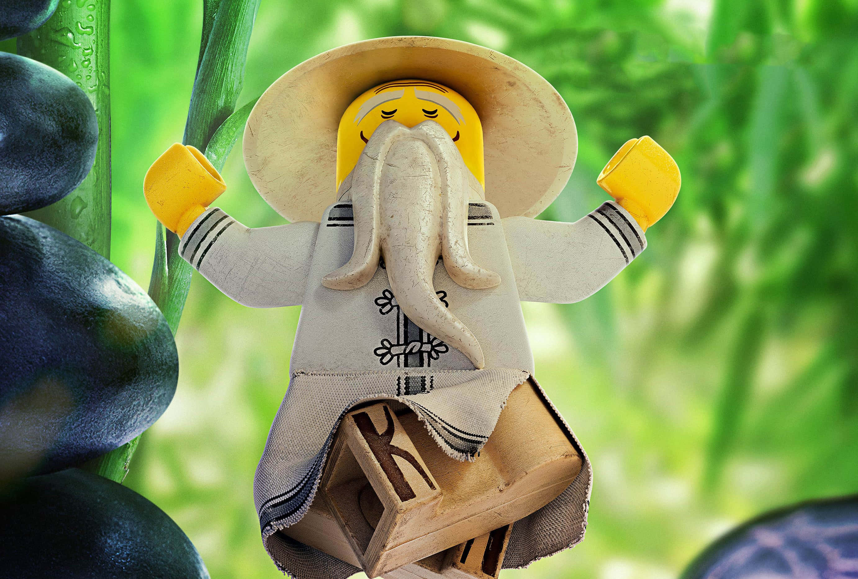 Animated 桌布 壁紙 — 一個擁有長長白鬍鬚和寬邊帽的LEGO迷你人偶，在茂密的綠葉中平靜地掛在竹莖上。
