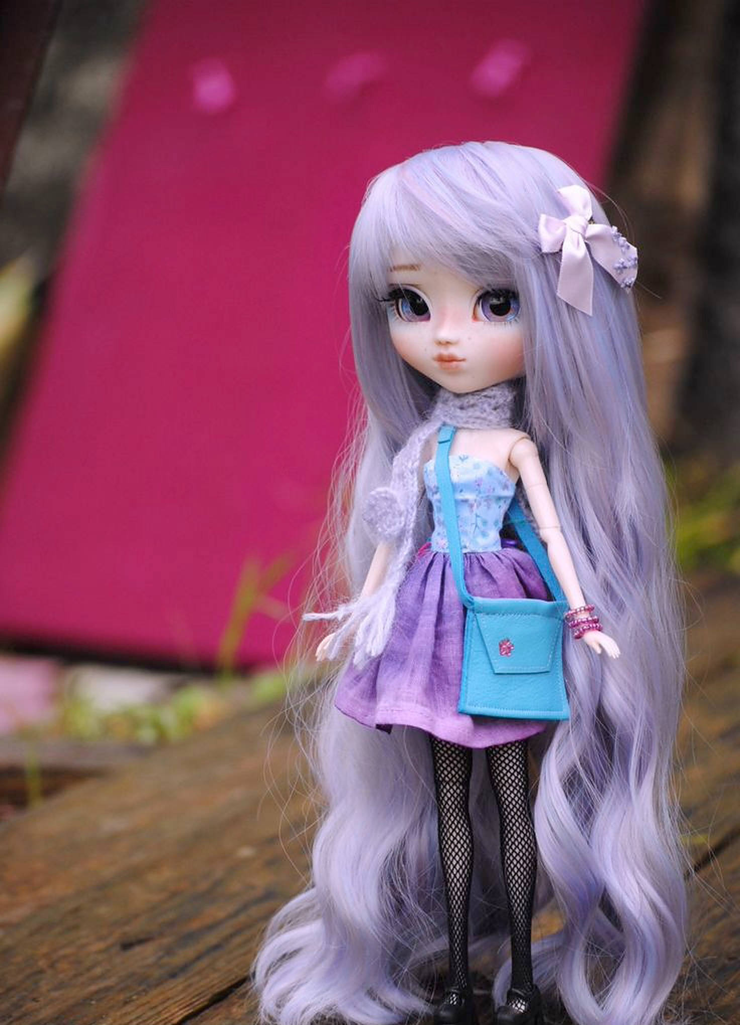 Doll 桌布 壁紙 — 一個擁有長長薰衣草色頭髮和藍色手提包的公仔，站在木質表面上，背景是模糊的粉紅色。