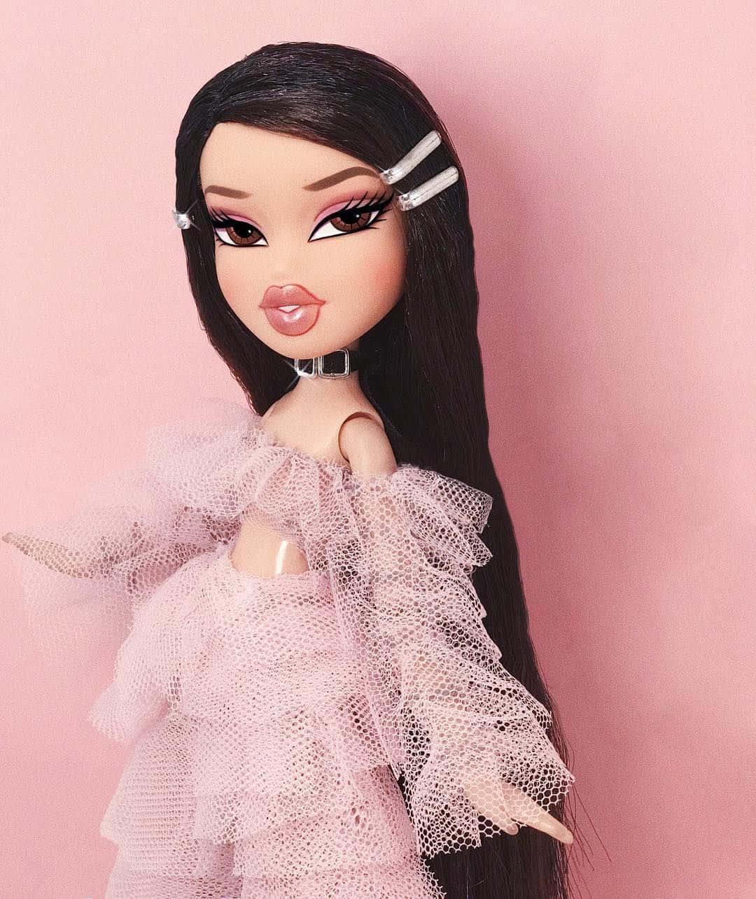 Bratz 桌布 壁紙 — 一個擁有長長黑髮和粉紅色薄紗裙的 Bratz 公仔，在柔和的粉紅色背景前擺姿勢。