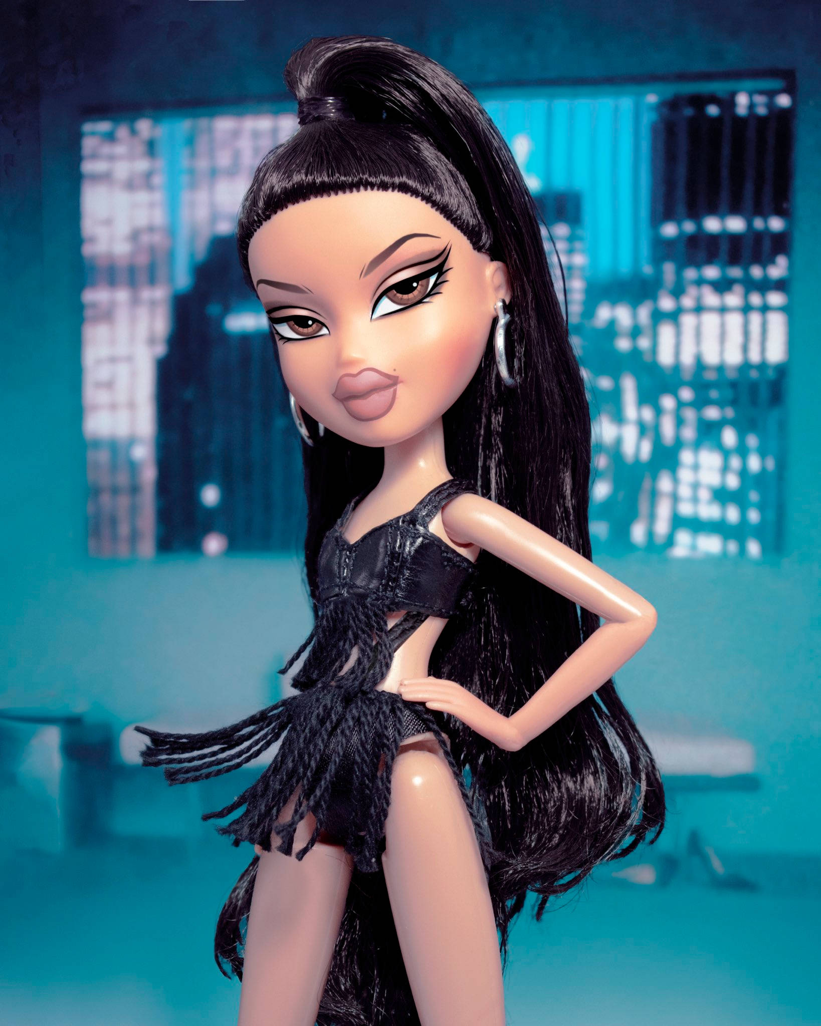 bratz 美學 桌布 壁紙 — 一個擁有長長黑髮和誇張妝容的 Bratz 公仔，穿著黑色流蘇服裝，在藍綠色城市景觀背景下自信地擺姿勢。