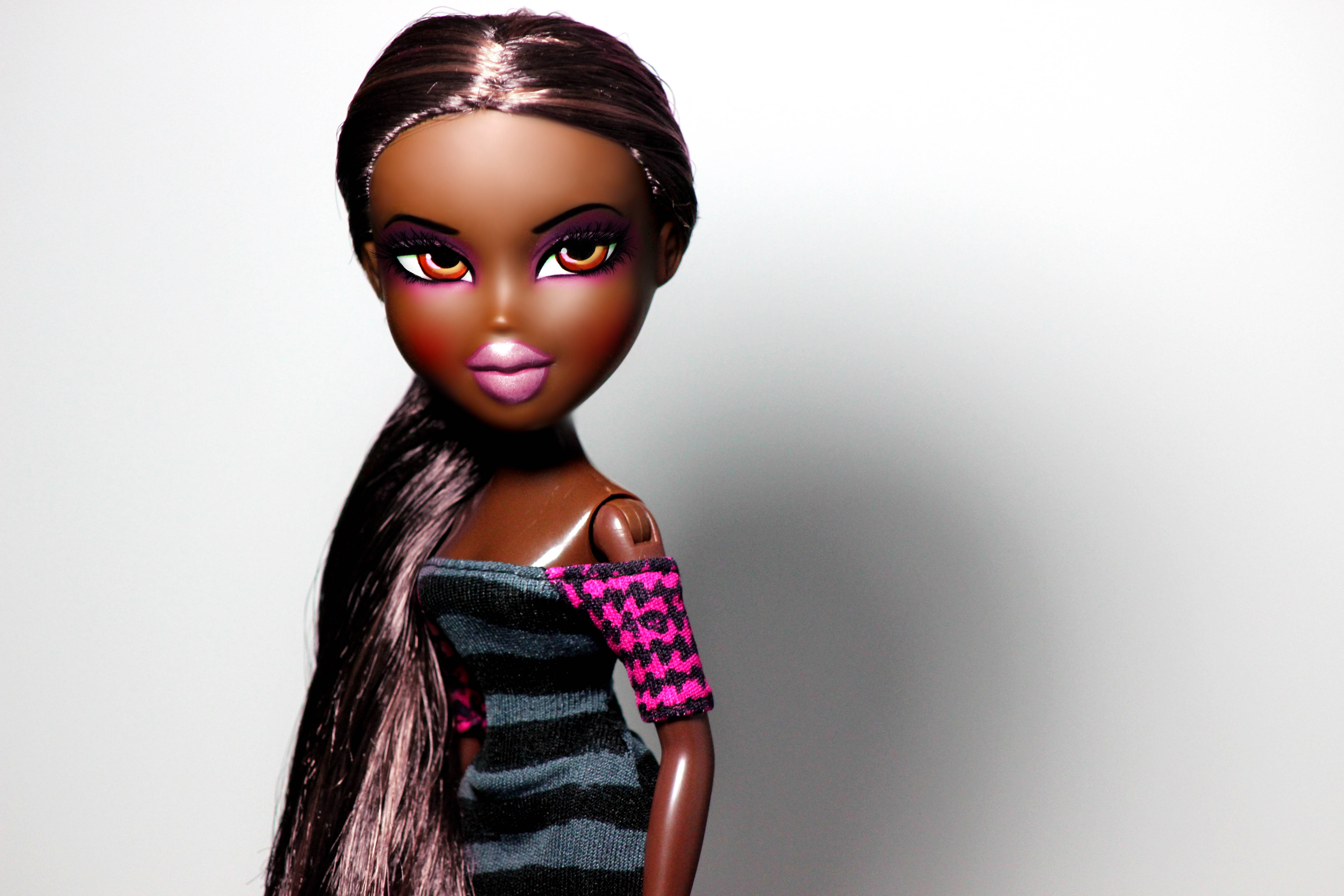 bratz 美學 桌布 壁紙 — 一個擁有長黑髮和誇張妝容的 Bratz 公仔，在純白背景前擺姿勢。