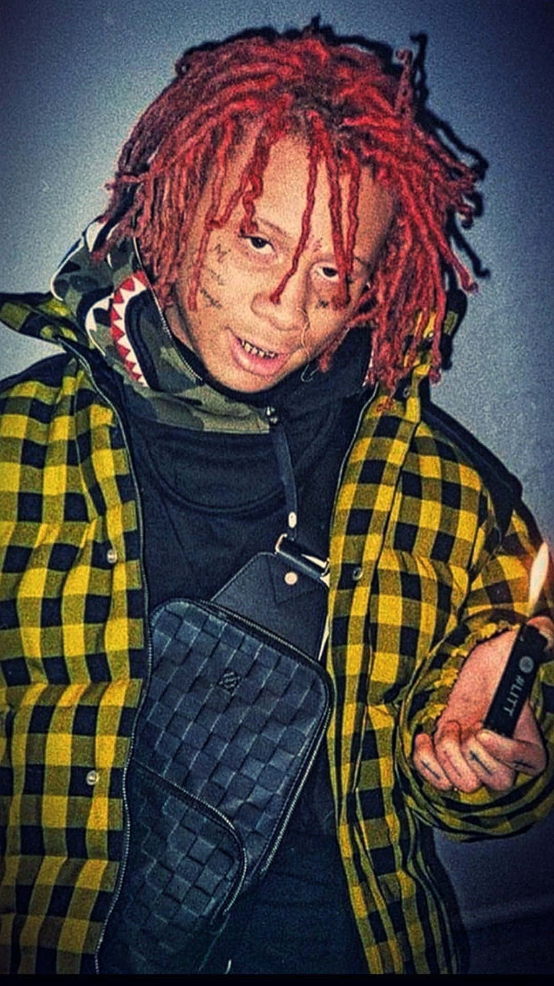 Trippie Redd 桌布 壁紙 — 一個擁有鮮紅色辮子頭和面部刺青的人，穿著黃黑格紋外套，手持點燃的打火機。