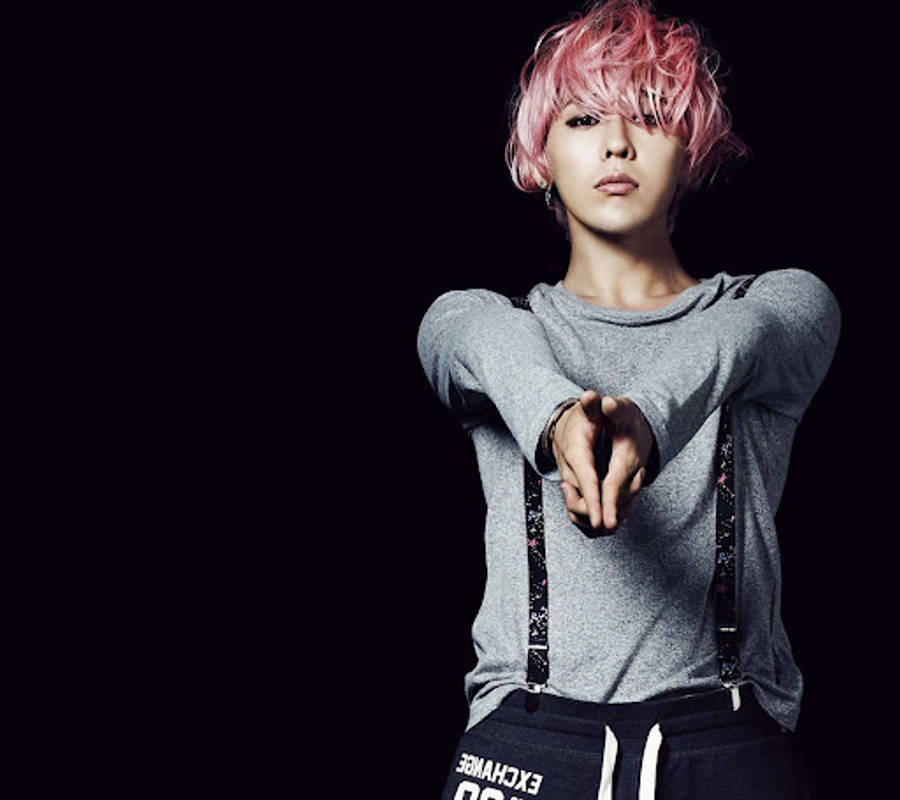 G-dragon 桌布 壁紙 — 一個擁有鮮豔粉紅色頭髮和灰色毛衣的人，在純黑背景下直接指向觀眾。