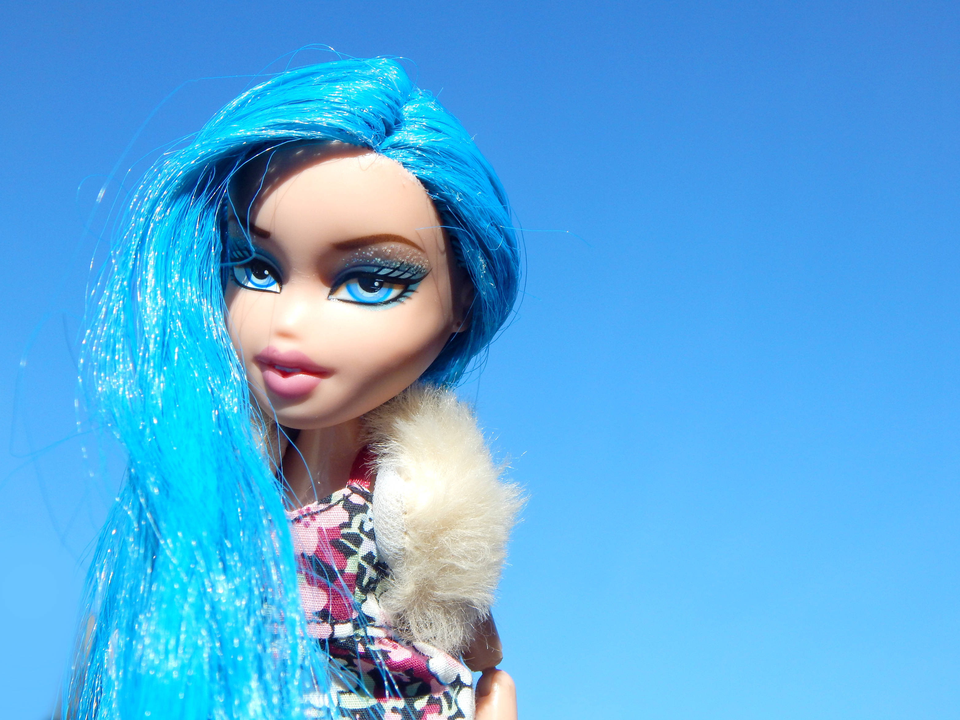 bratz 美學 桌布 壁紙 — 一個擁有鮮豔藍色頭髮和閃亮眼睛的洋娃娃，凝視著清澈的藍天。