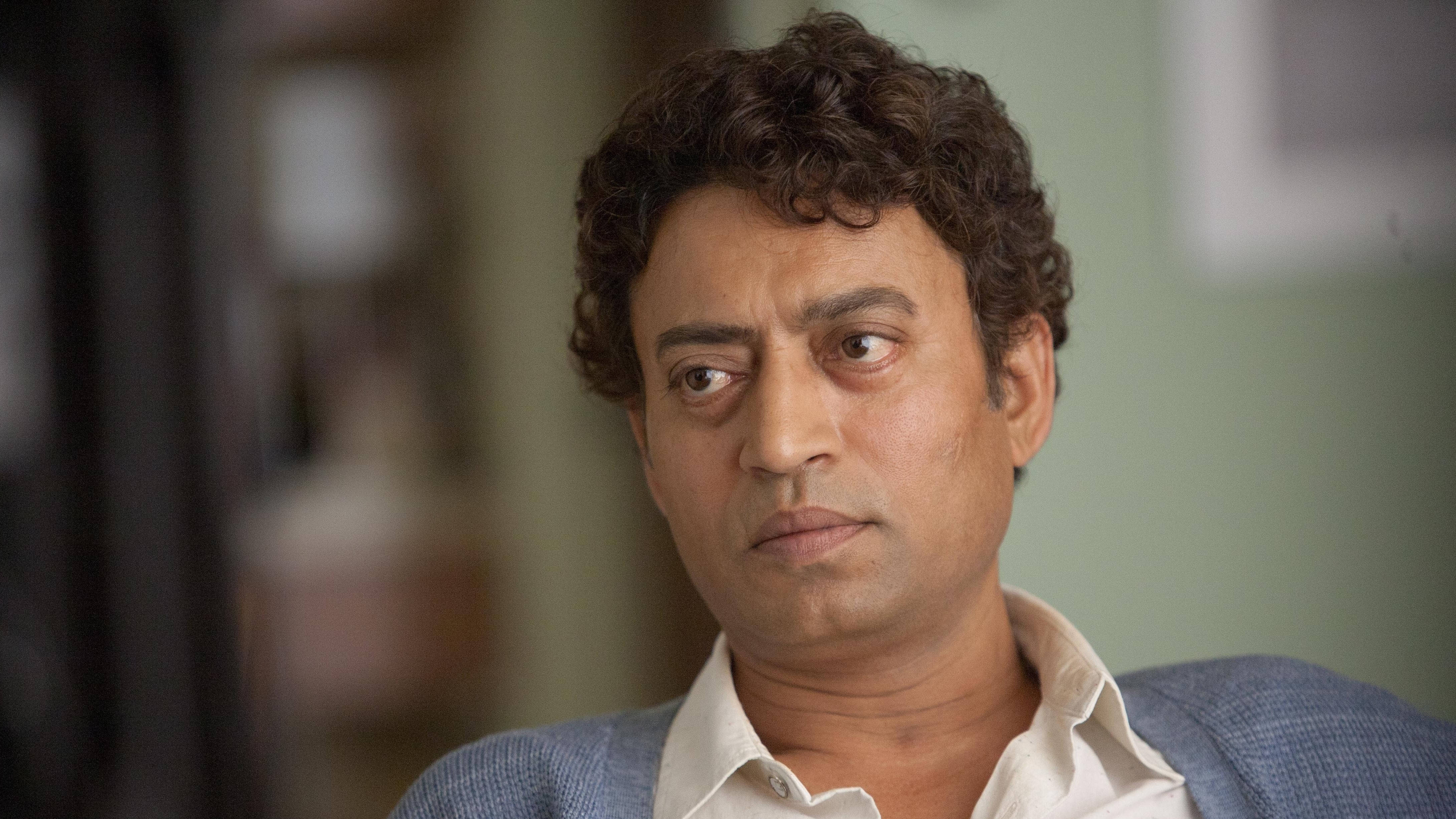 Irrfan Khan 桌布 壁紙 — 一個擁有黑色捲髮的男人在柔和光線的室內環境中，表情嚴肅地望向一旁。