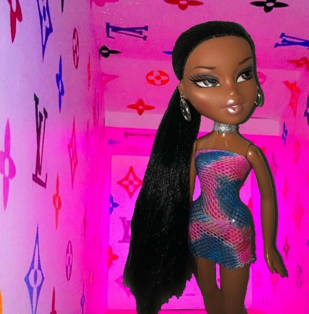 少女風 桌布 壁紙 — 一個擁有黑色長髮和銀色圓環耳環的 Bratz 公仔，站在一面佈滿彩色 Louis Vuitton 字母圖案的粉紅色牆前。
