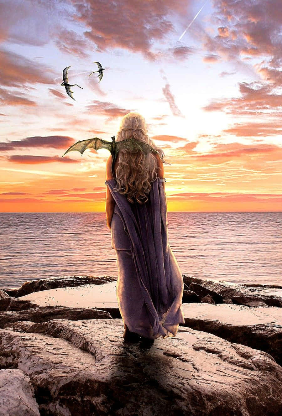 Game Of Thrones iPhone 桌布 壁紙 — 一個擁有龍翼的女人站在岩石懸崖上，在日落時分看著兩條龍在火熱的橙色和紫色天空中翱翔。
