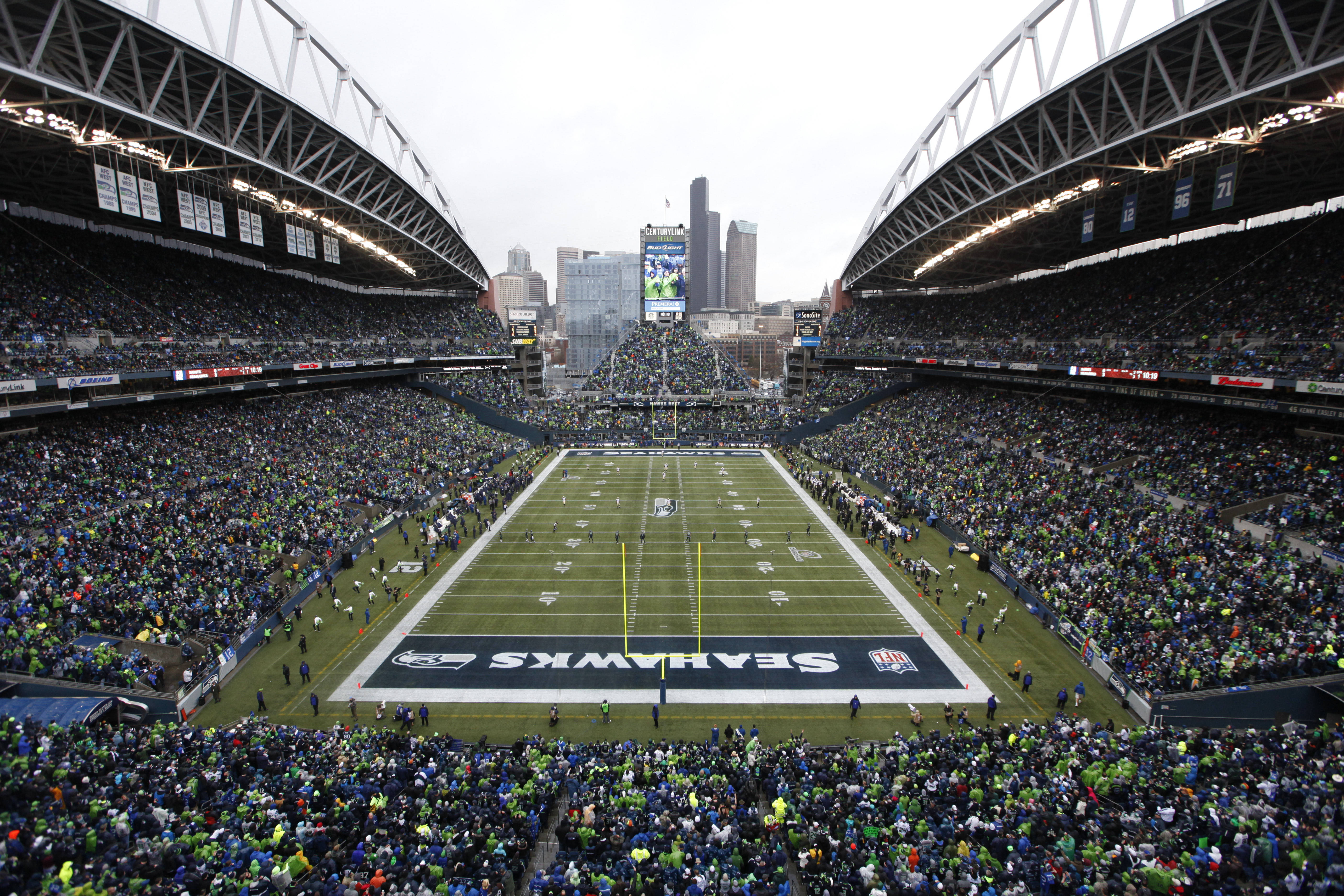Seattle Seahawks 桌布 壁紙 — 一個擠滿了身穿綠色和藍色服裝的球迷，在陰天歡呼的西雅圖海鷹隊體育場。